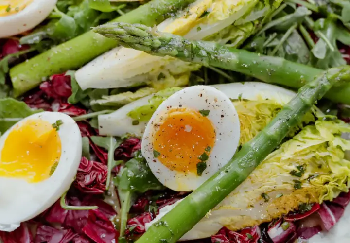 Salade colorée avec des œufs mollets, des asperges vertes croquantes et des feuilles de laitue et de radicchio.