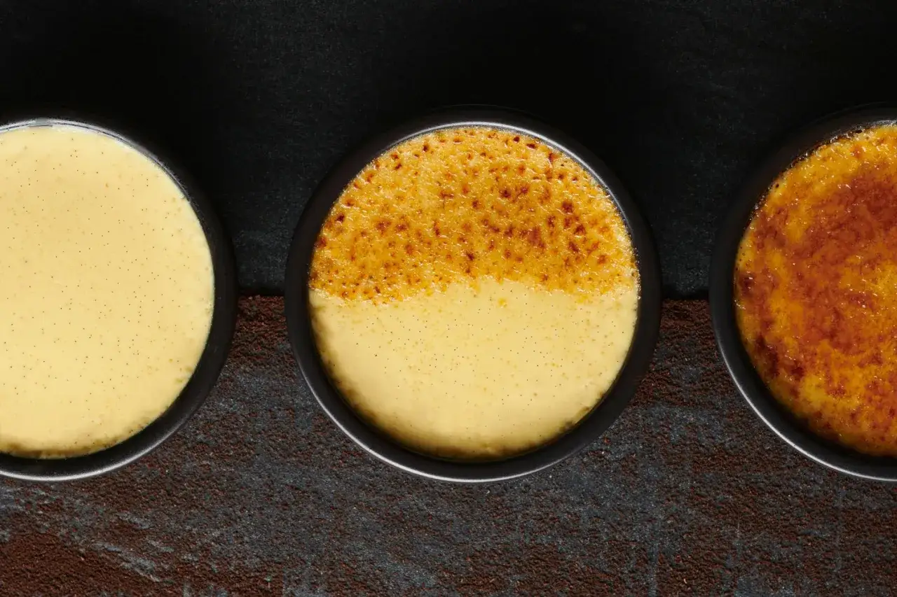 Trois ramequins de cr&egrave;me br&ucirc;l&eacute;e, dont un &agrave; la cro&ucirc;te caram&eacute;lis&eacute;e parfaite.