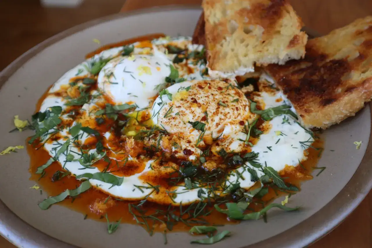 &OElig;ufs poch&eacute;s sur un lit de yaourt, arros&eacute;s d'huile &eacute;pic&eacute;e et d'herbes fra&icirc;ches. Une d&eacute;licieuse recette de cilbir pour un brunch parfait.